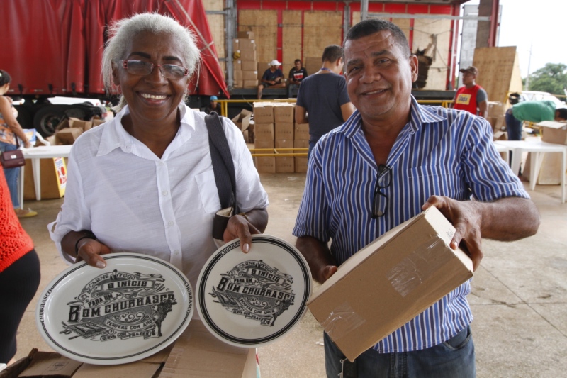 A aposentada Maria Pereira e o vendedor Janai Pereira da Silva retiram o Kit Churras no Espaço Cultu